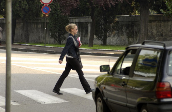 Frau geht ueber einen Schutzweg / Zebrastreifen