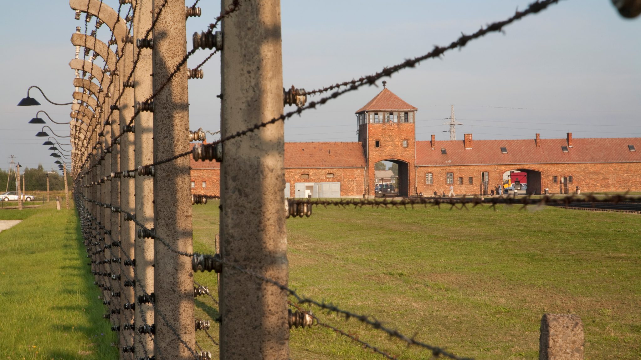 View Of The Main Guard House Through The Electrified Barbed Wire Fence Separating Sections Of The Auschwitz Birkenau Concentration Camp, Oswiecim, Malopolska, Poland