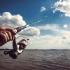 Closeup of a boys hand holding a fishing rod and reel