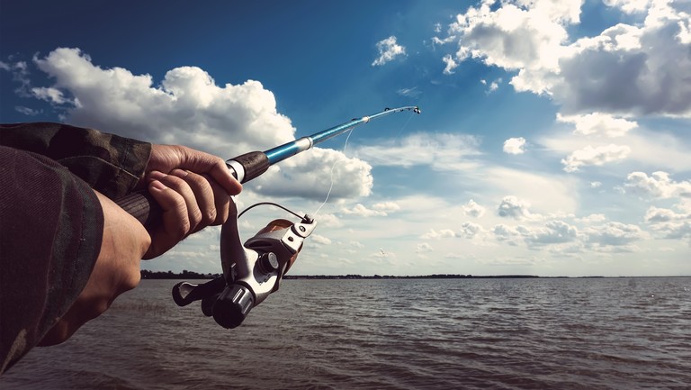 Closeup of a boys hand holding a fishing rod and reel