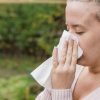 Attractive woman outdoor with tissue having allergy. woman blowi