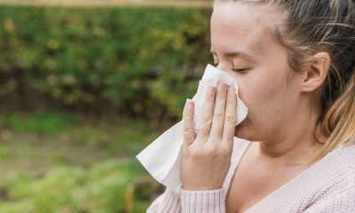 Attractive woman outdoor with tissue having allergy. woman blowi