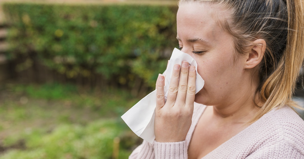 Attractive woman outdoor with tissue having allergy. woman blowi
