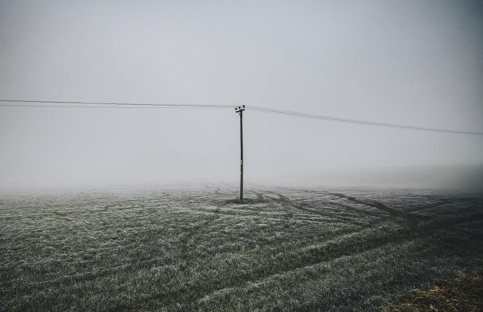 Frosty field with electric pole in a misty day